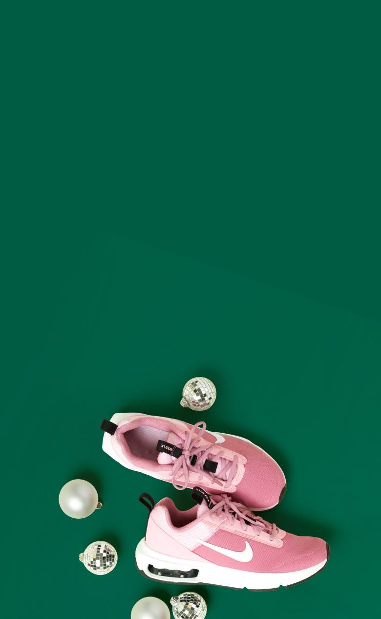 Pink Nike sneakers and disco ball ornaments against a green background