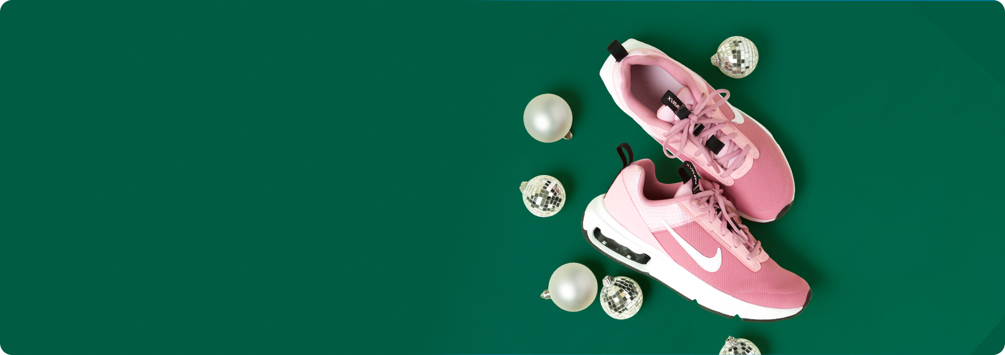 Pink Nike sneakers and disco ball ornaments against a green background